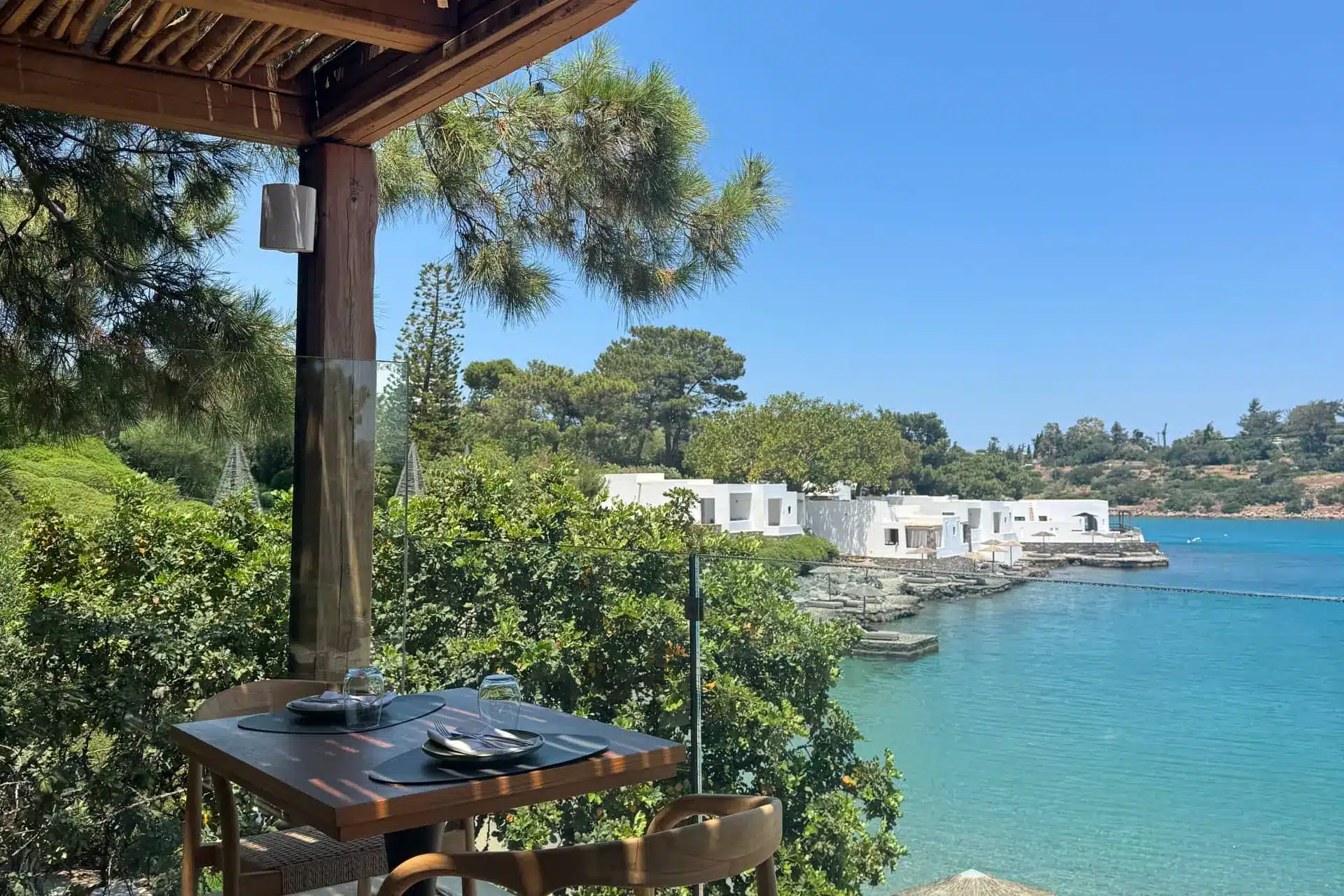 Terrace dining setup overlooking calm turquoise bay and white waterfront hotel
