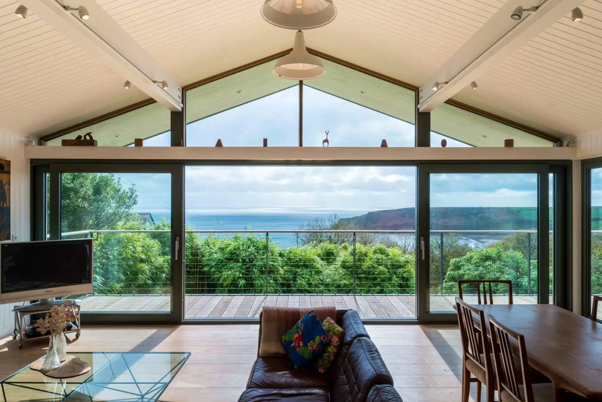 Luxury open-plan living room with ocean views, seating, and dining table under a vaulted ceiling