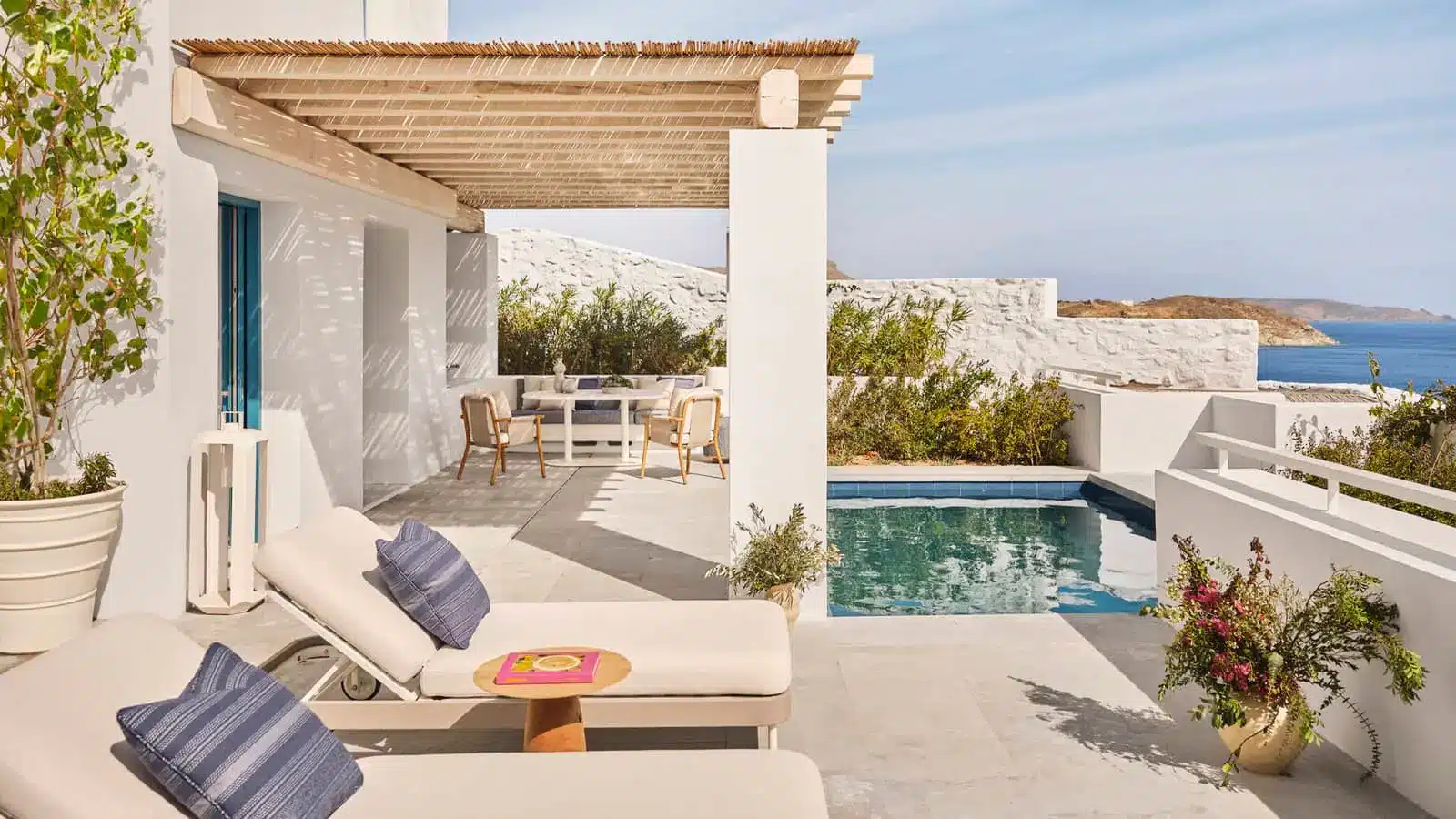 Luxury villa terrace with sun loungers, pool, and ocean view in warm coastal light