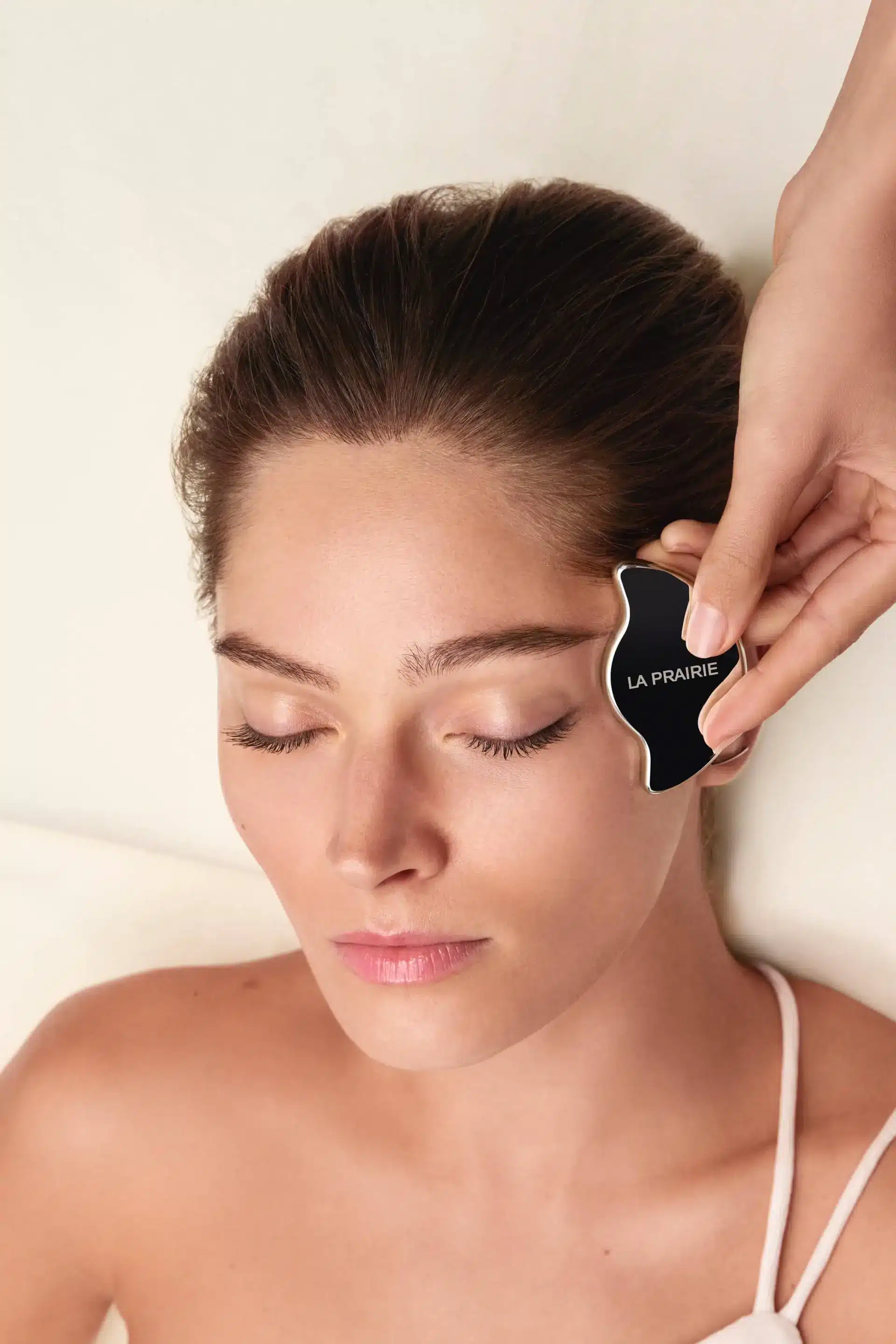 Woman receives luxury facial massage with gua sha tool at a spa, eyes closed