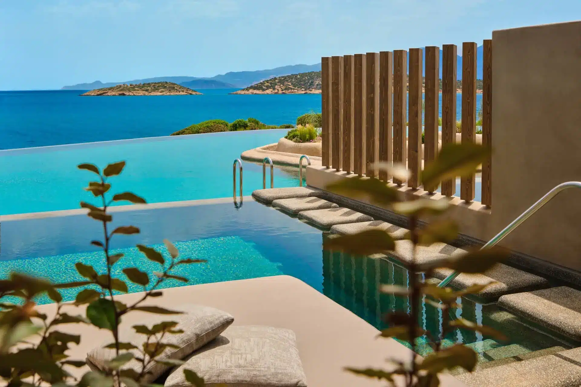 Luxury resort terrace with sunbeds overlooking turquoise sea and islands at sunset