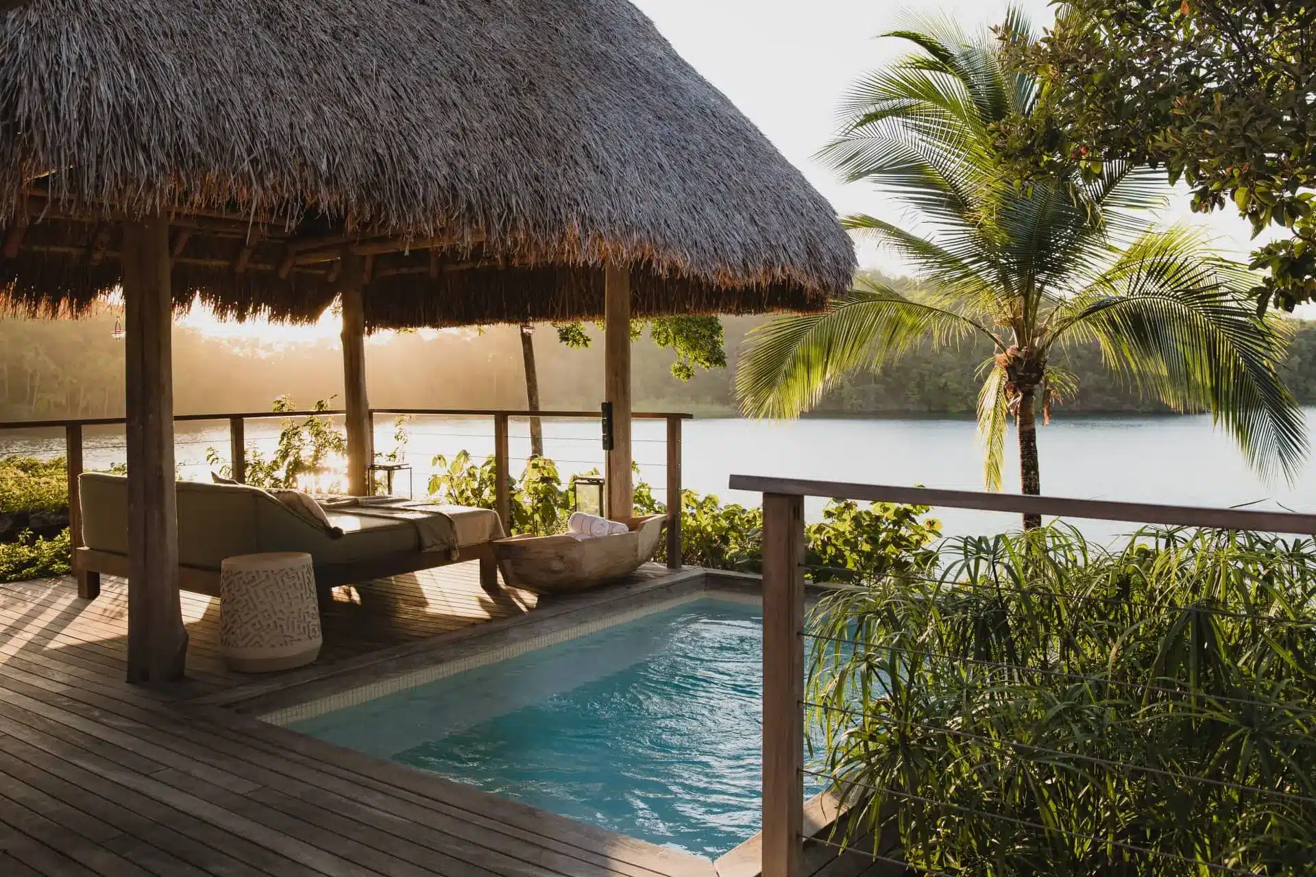 Luxury tropical villa with a private pool, thatched pavilion, palm trees, and lagoon views