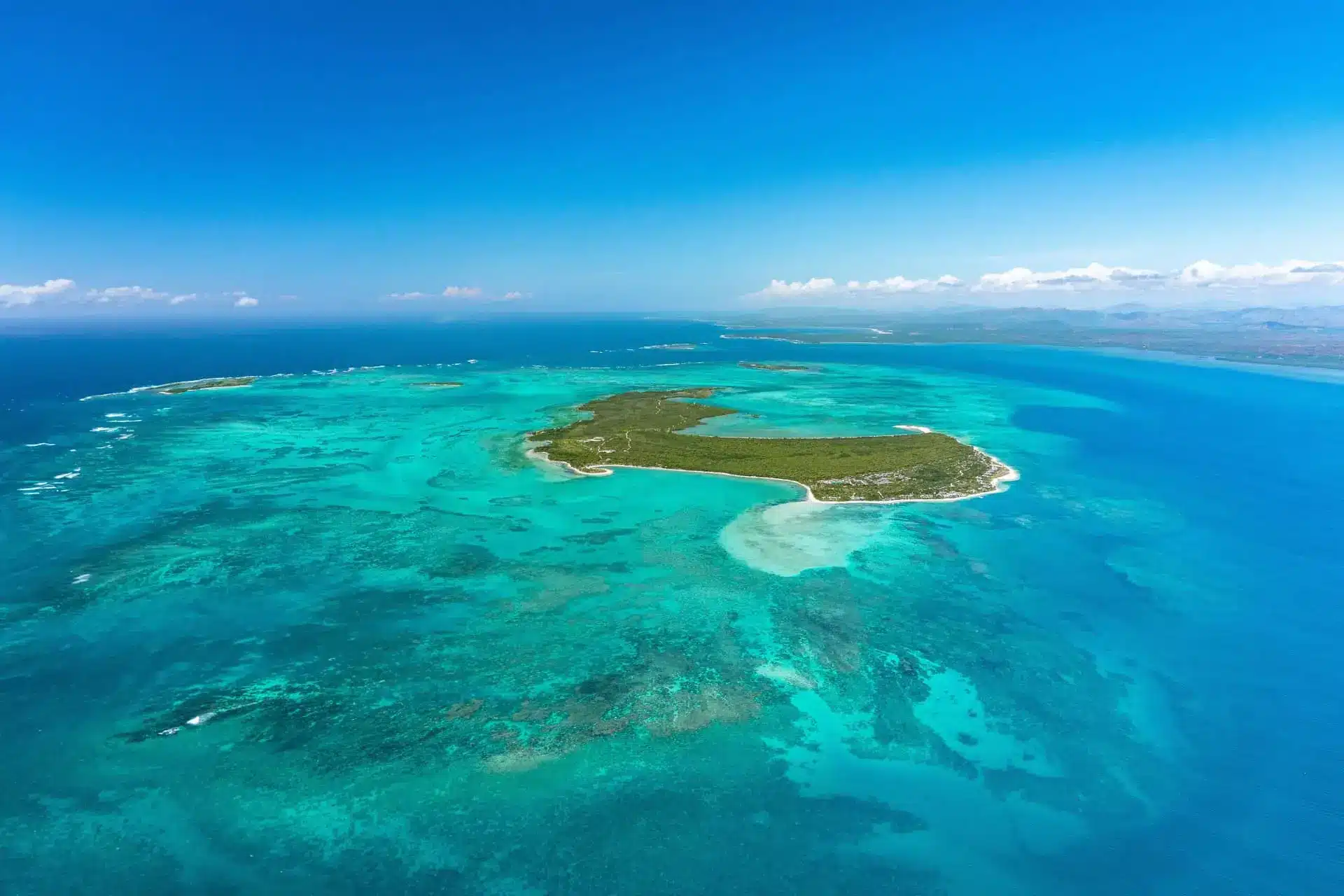 Aerial view of a tropical island surrounded by turquoise lagoon waters and coral reefs