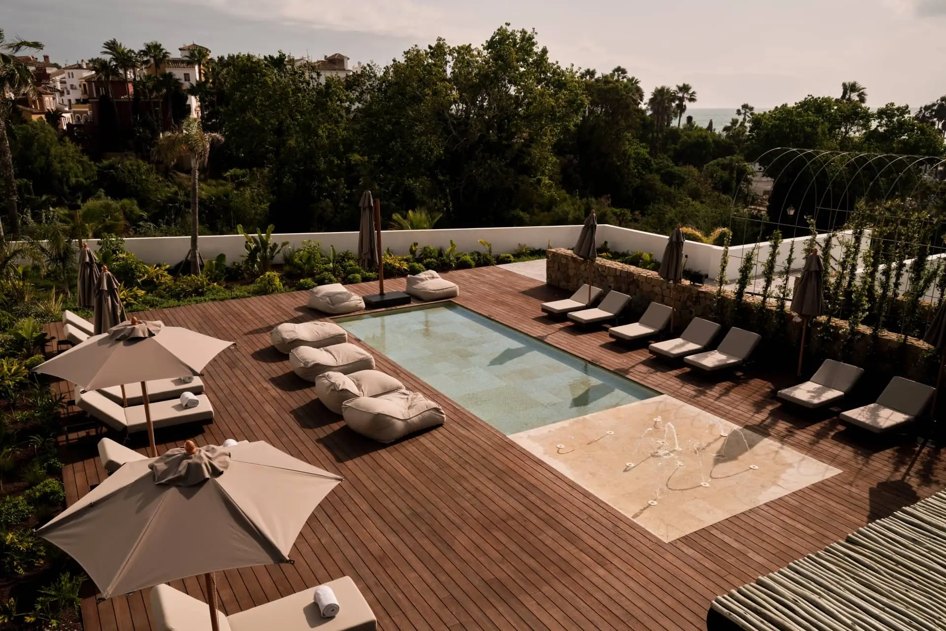 Luxury resort pool deck with loungers, umbrellas, and lush tropical gardens