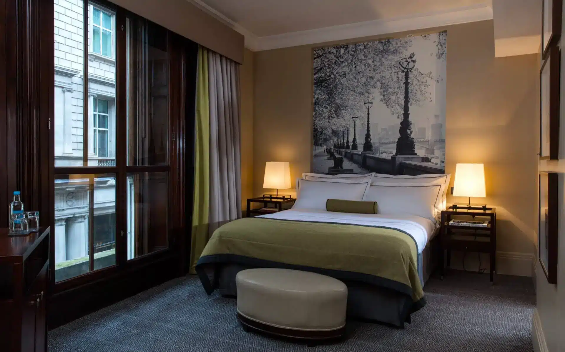 Elegant luxury hotel bedroom with a city view, king bed, and framed monochrome artwork