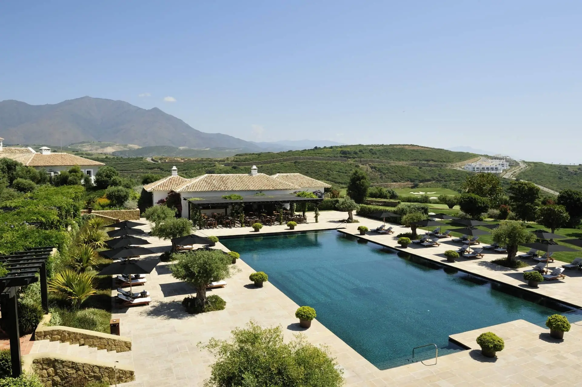 Luxury resort pool surrounded by landscaped gardens and mountain scenery
