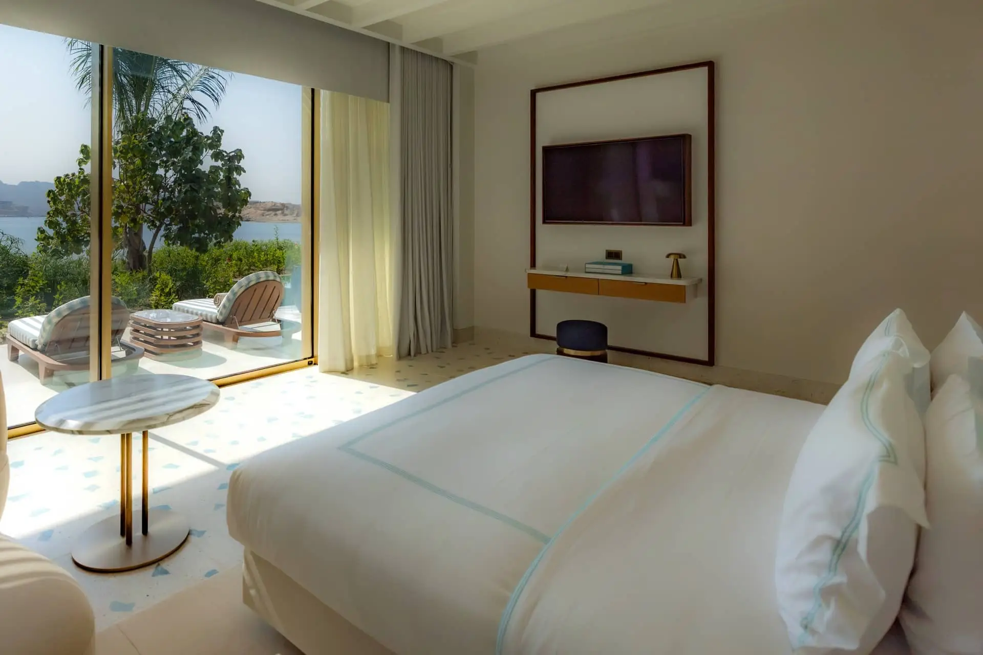 Luxury hotel bedroom with a sea view, private terrace, and bright modern interiors