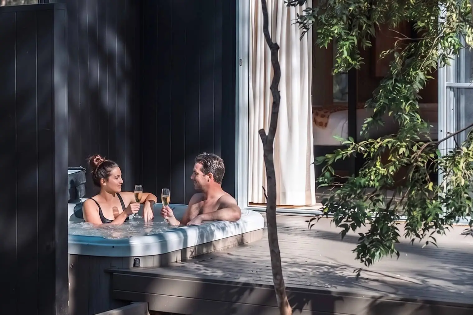 Couple enjoying drinks together in a private outdoor hot tub