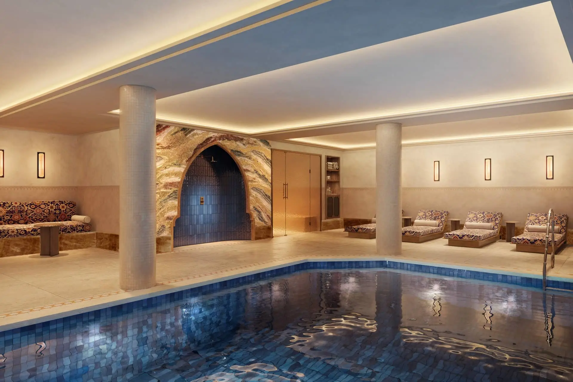 Luxury indoor pool with blue tiled water, arched doorway, columns, and lounge seating