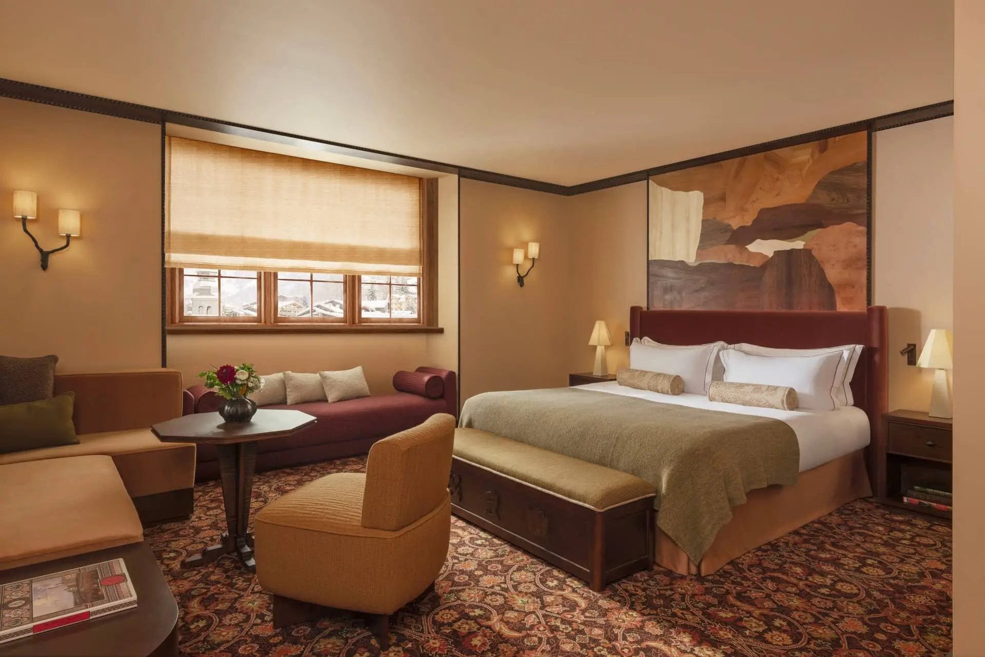 Saint Roch hotel room with a king bed, mountain mural, patterned carpet and seating area