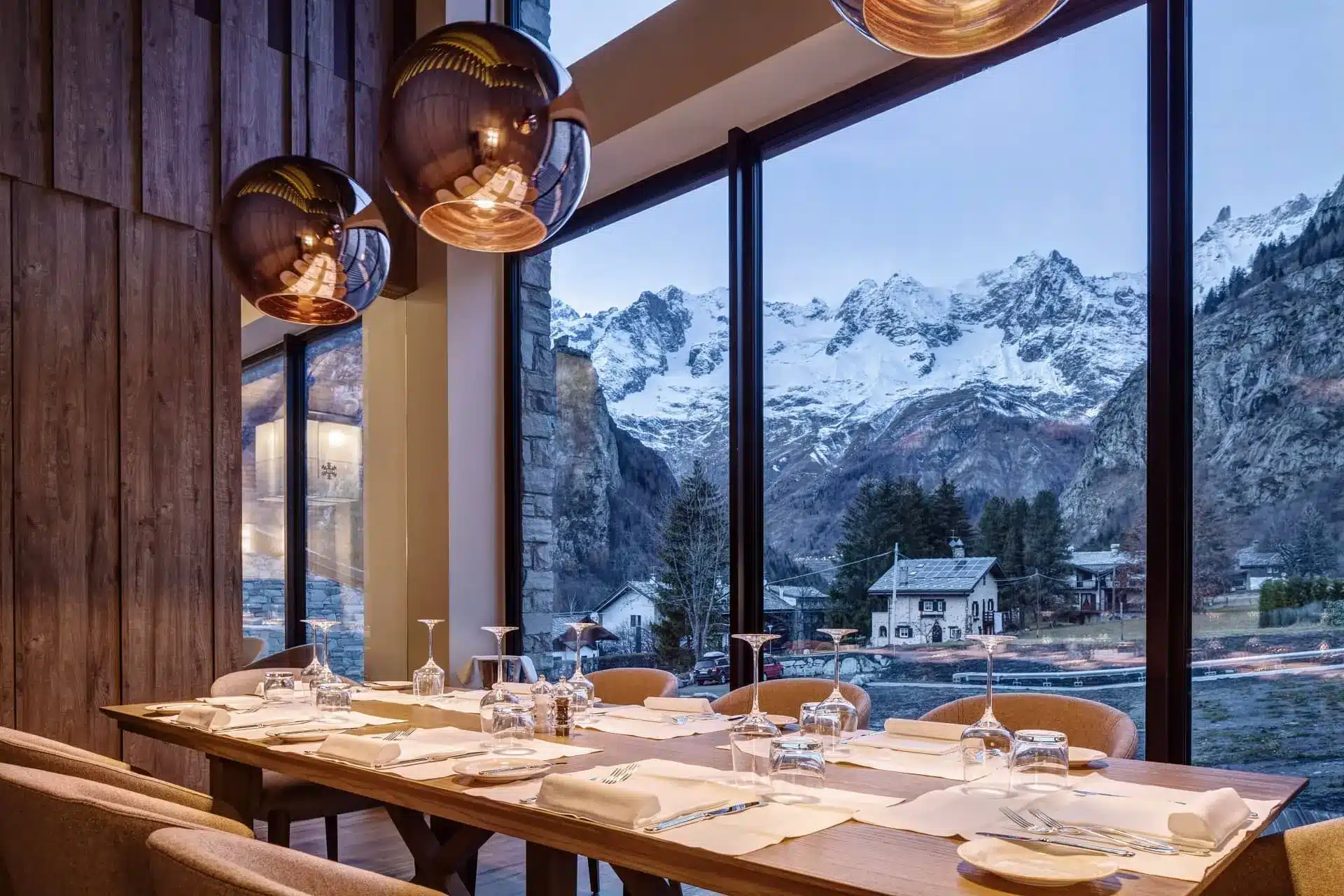 Elegant mountain restaurant dining room with a set table overlooking snow-capped Alpine peaks