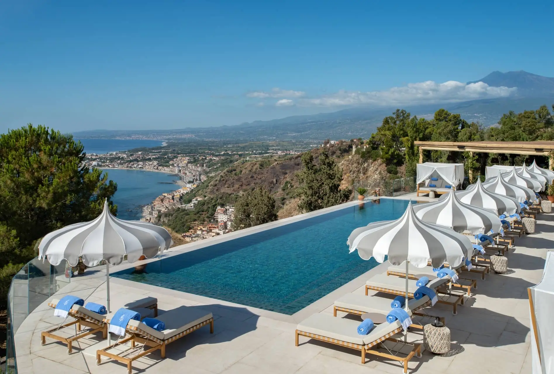 Luxury infinity pool overlooking a coastal town and mountain landscape