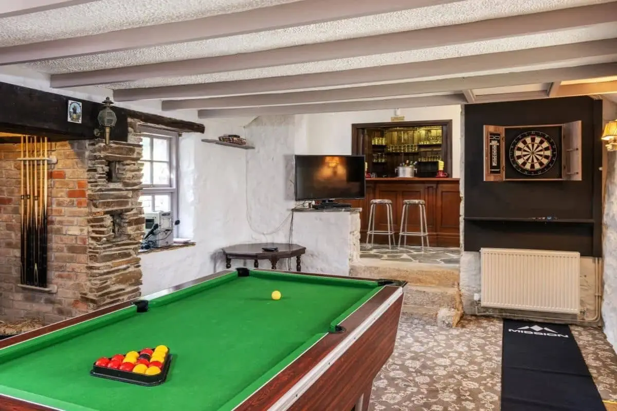 Games room at Hembal Manor, with a pool table in the foreground and a dartboard on the wall.