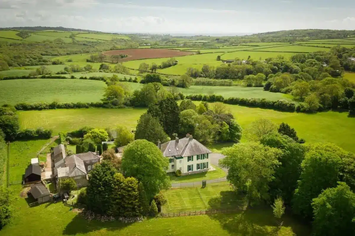 Elm Grove Country House, a white country manor set among green lawns and trees in the Pembrokeshire countryside.