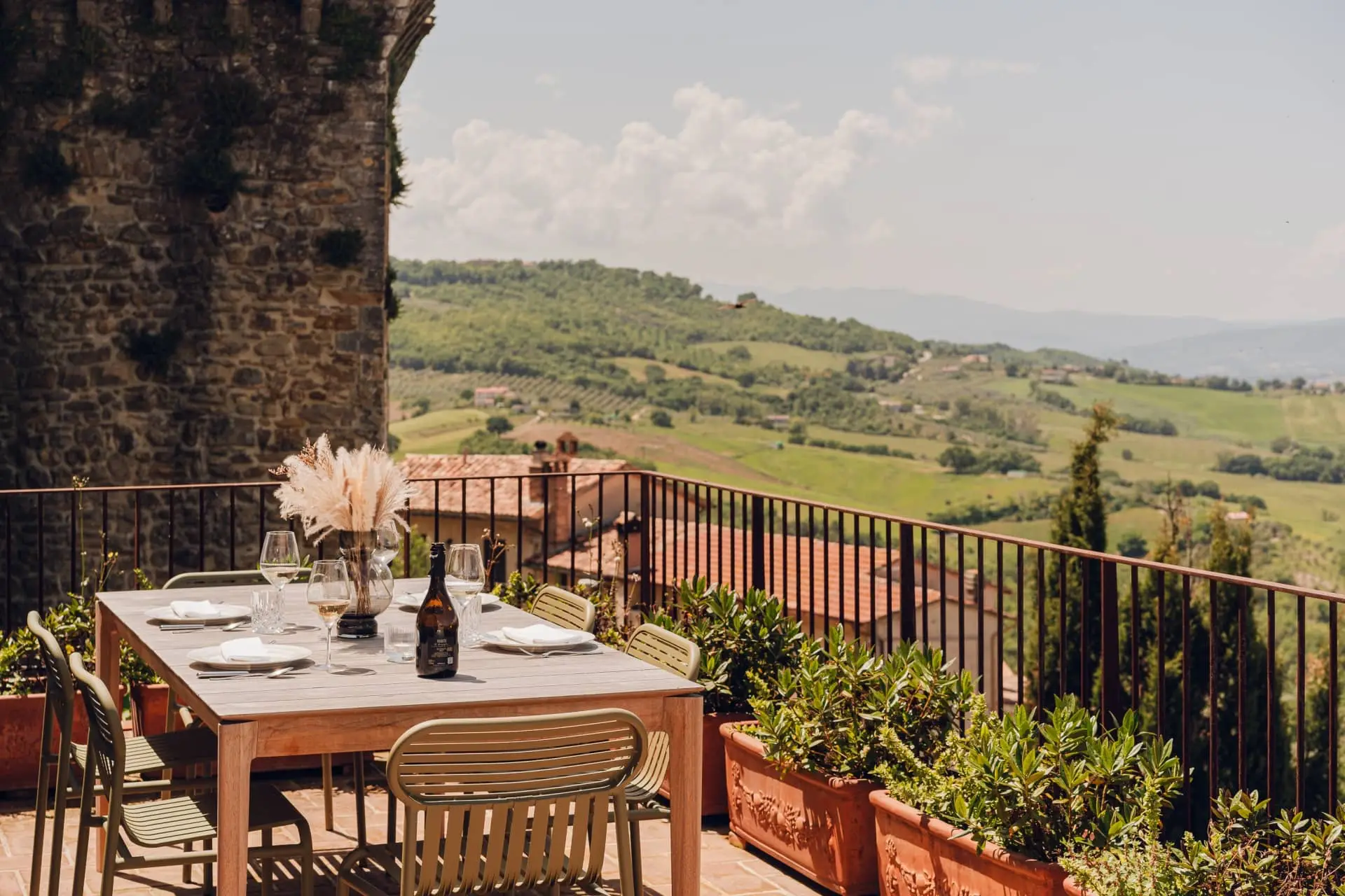 Elegant terrace dining table overlooking rolling green hills and a sunlit countryside landscape