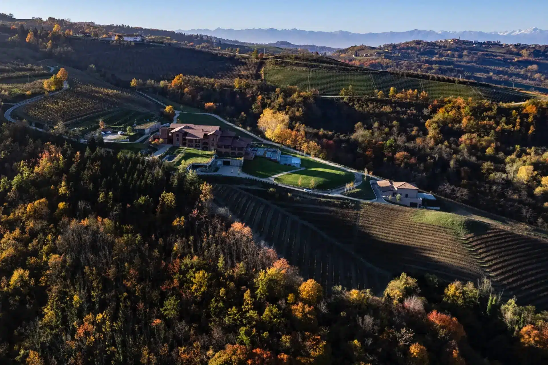 Aerial view of a luxury vineyard estate surrounded by autumn hills and distant mountains