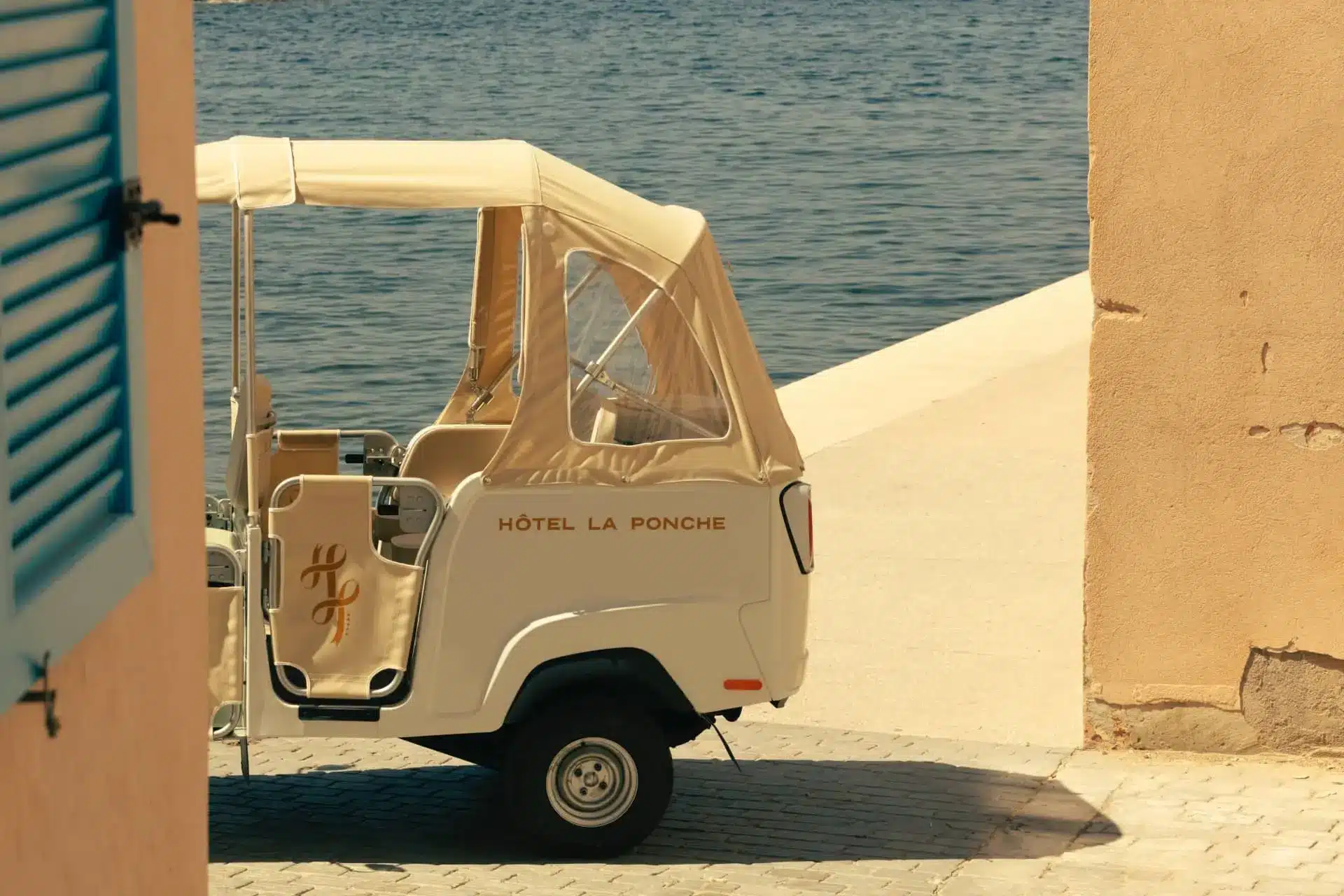 Vintage Hotel La Ponche tuk-tuk parked beside the sea in warm Mediterranean sunlight