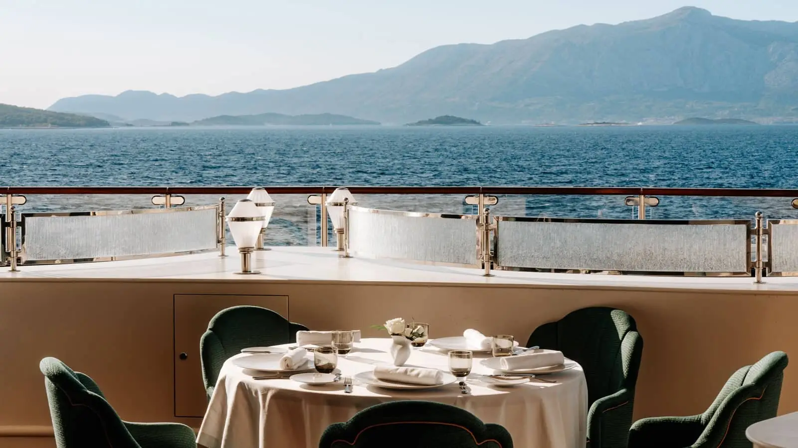 Elegant dining room aboard a vessel overlooking a mountain-framed bay
