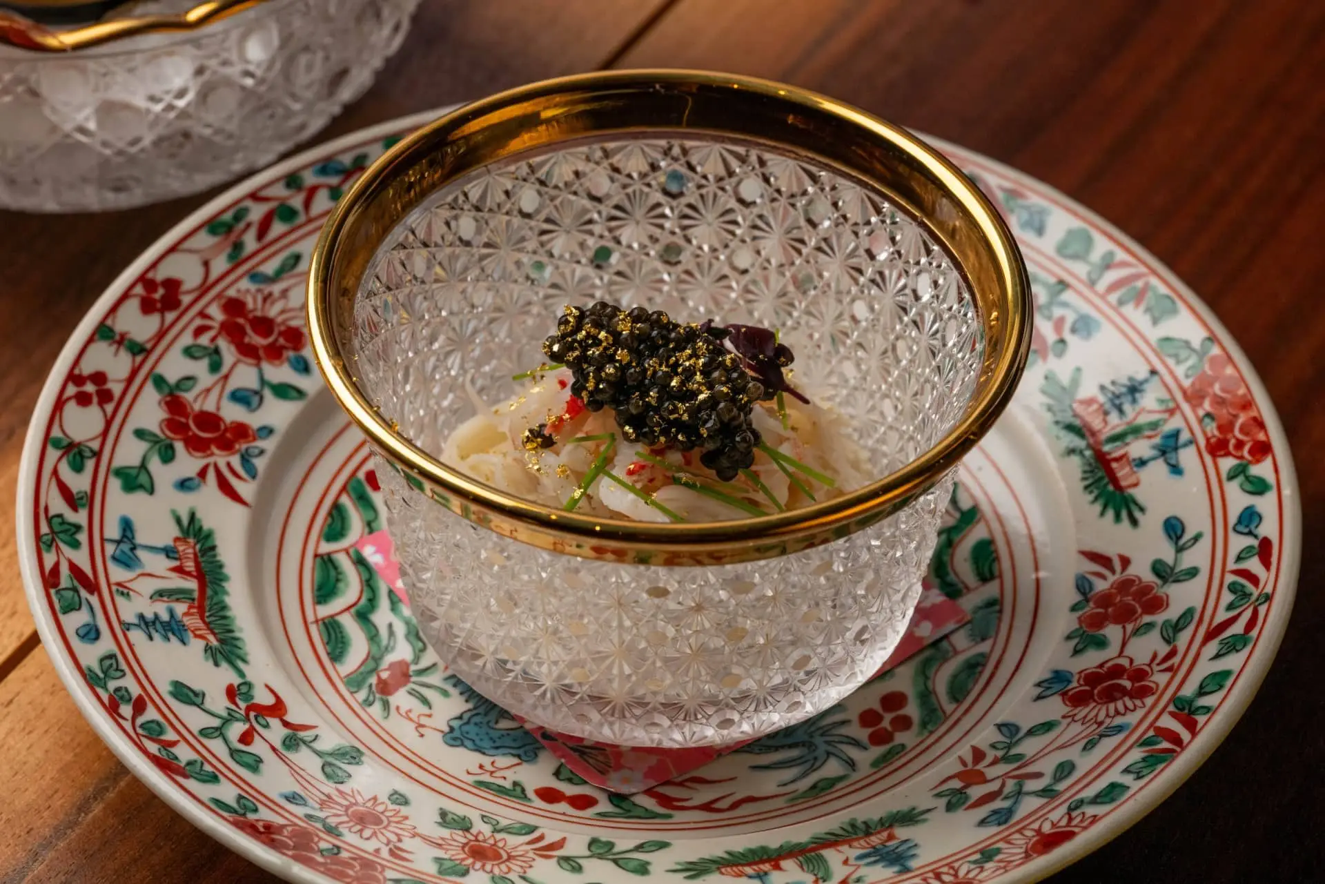 Caviar-topped gourmet dish in a crystal bowl on an ornate porcelain plate.