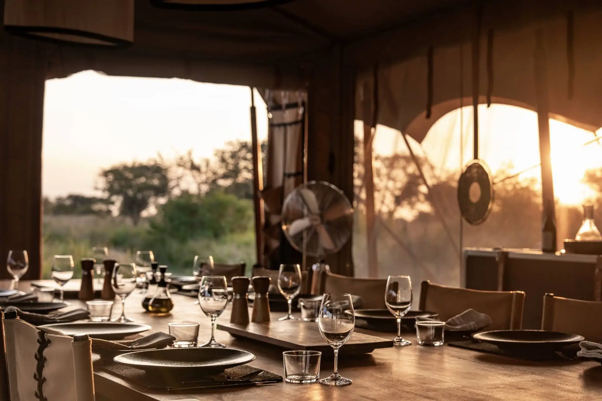 Elegant restaurant dining room with glassware set against large windows at sunset