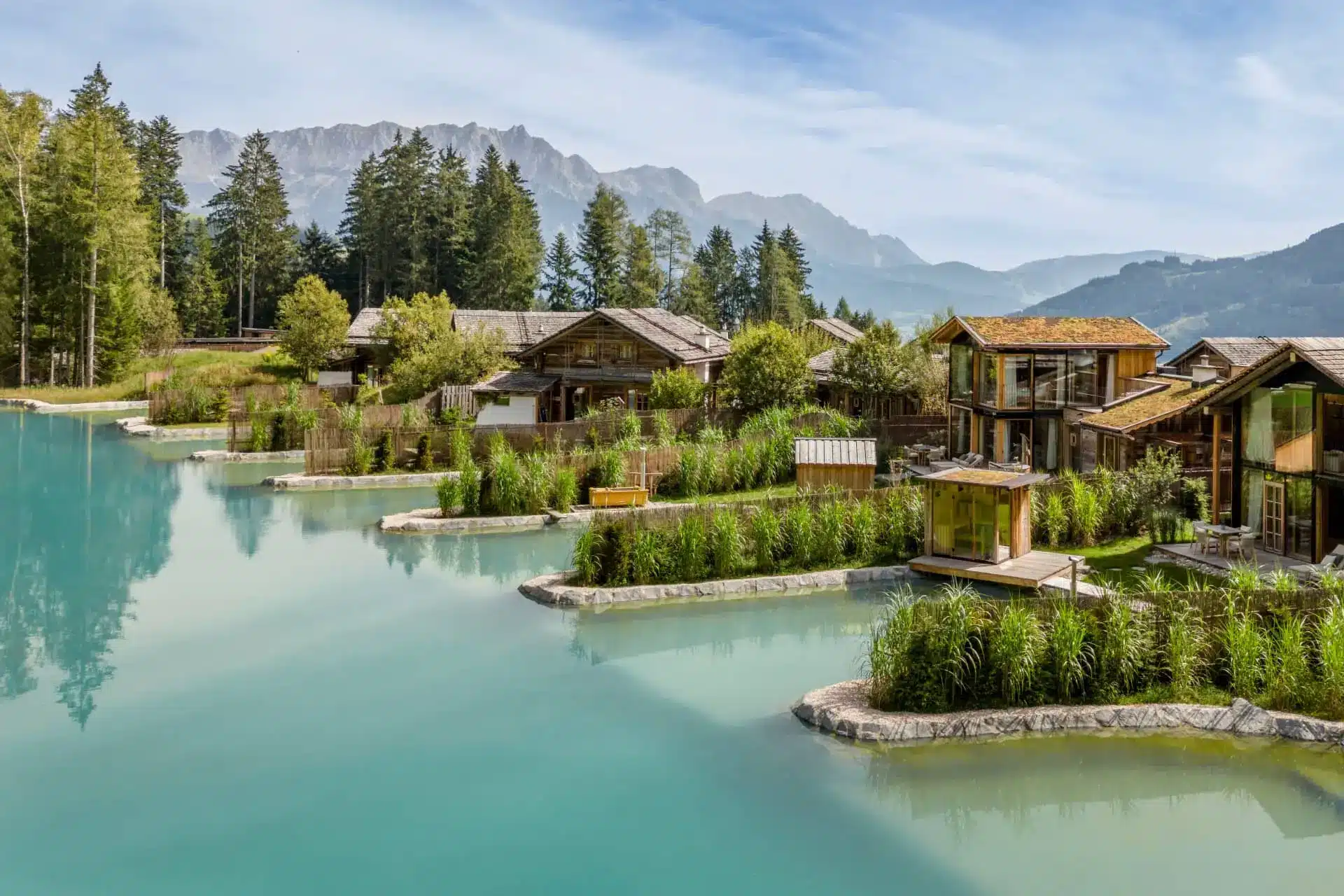 Luxury alpine resort with wooden chalets beside turquoise lagoons and forested mountain peaks