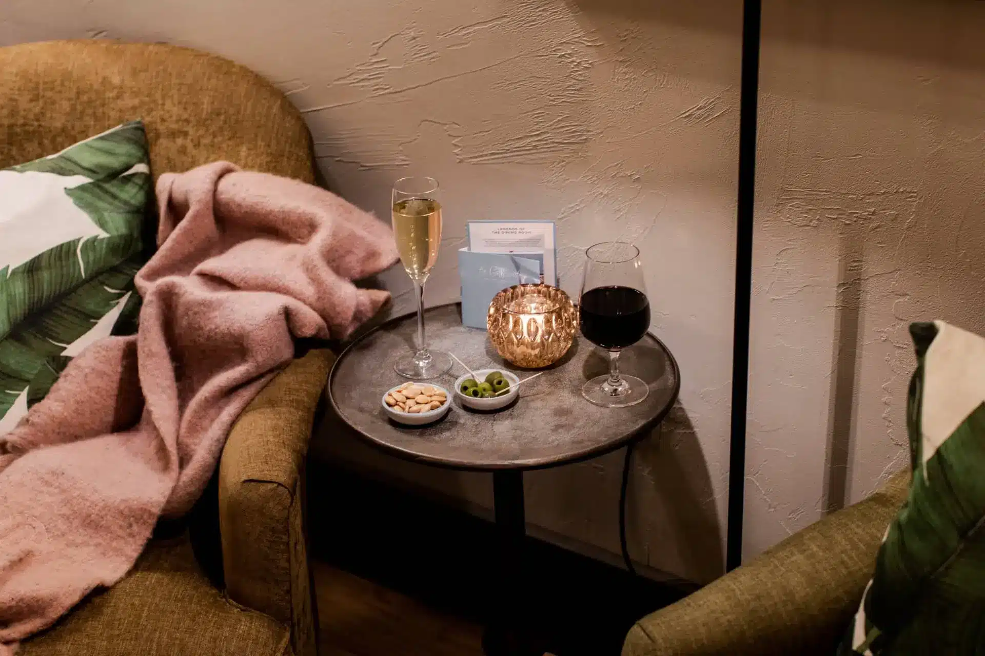 Cozy lounge corner with champagne, red wine, snacks, and a glowing candlelit table