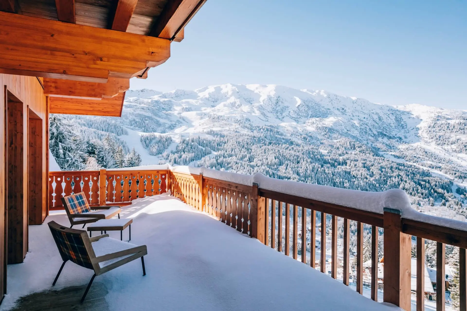 Snow-covered balcony with lounge chairs overlooking the Alpine mountains in Méribel