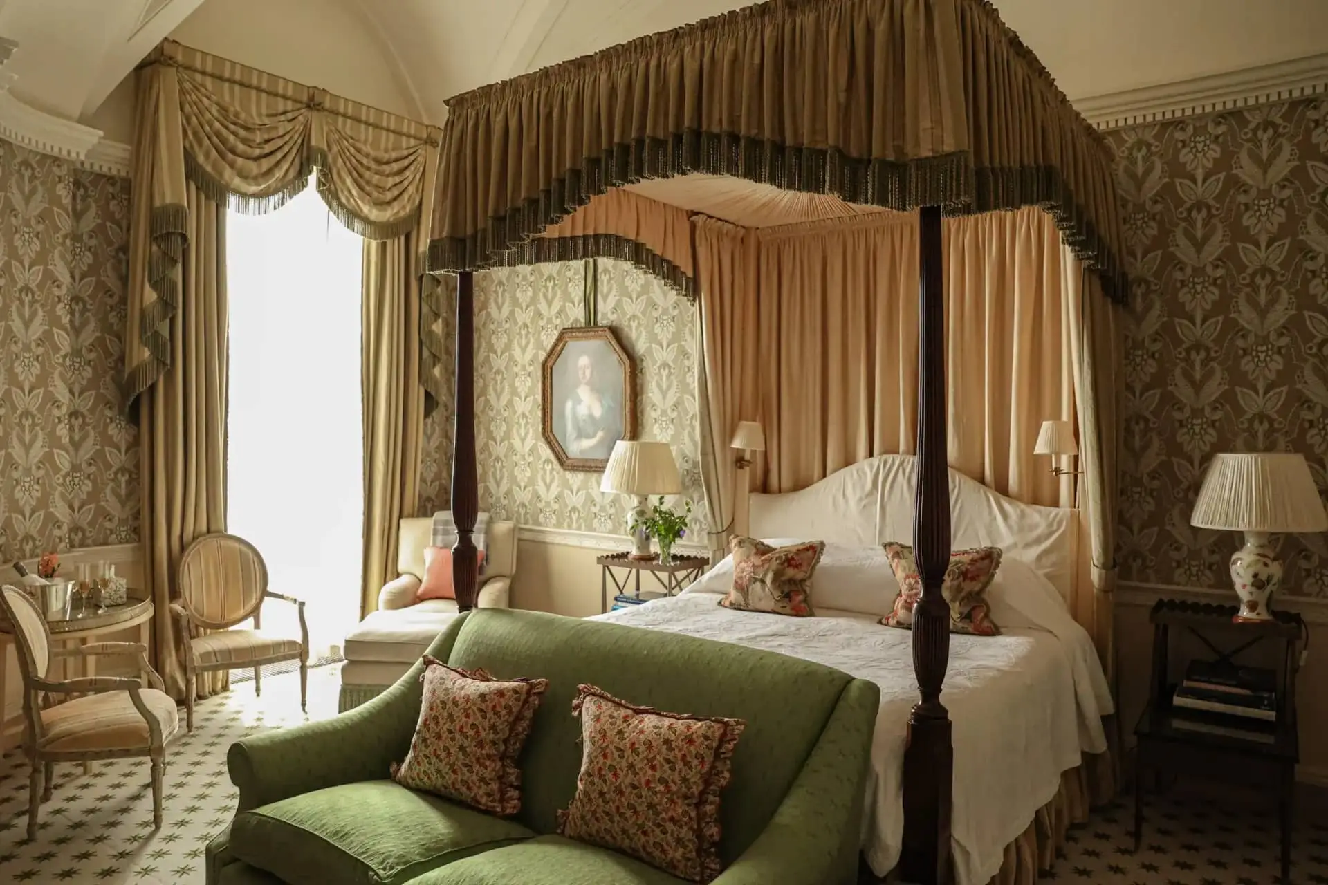 A canopied four-poster bed and green sofa in an ornate Regency-style bedroom at Ballyfin.
