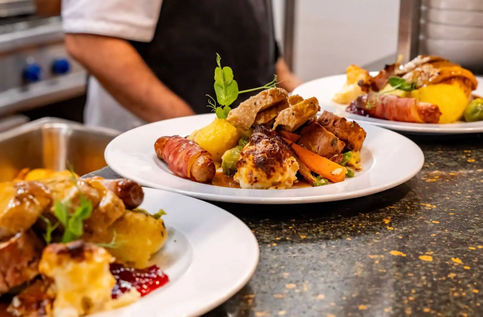 Chef plating a colorful gourmet dish with vegetables and roasted ingredients