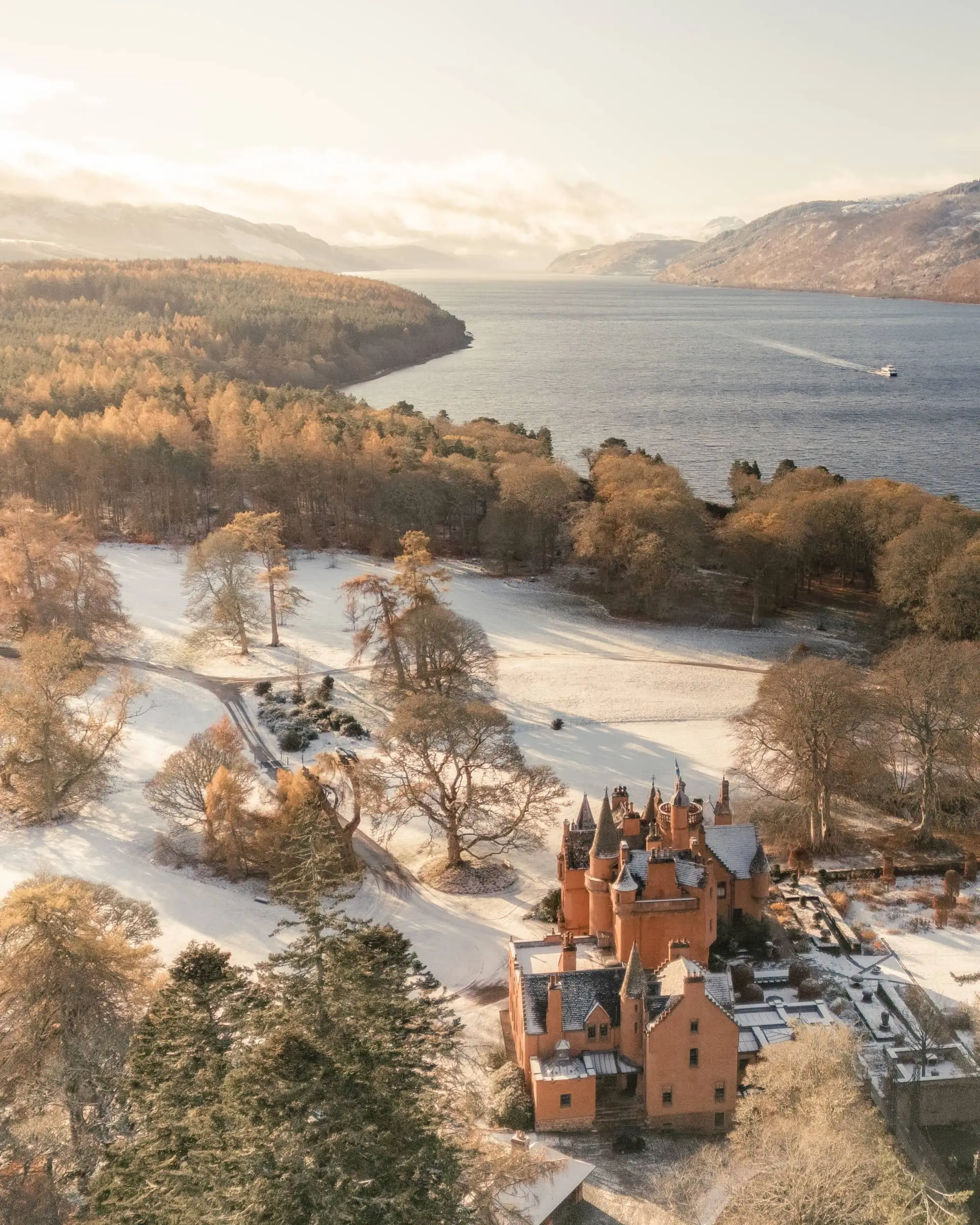 Aldourie Castle beside the snowy grounds of its wooded Loch Ness estate