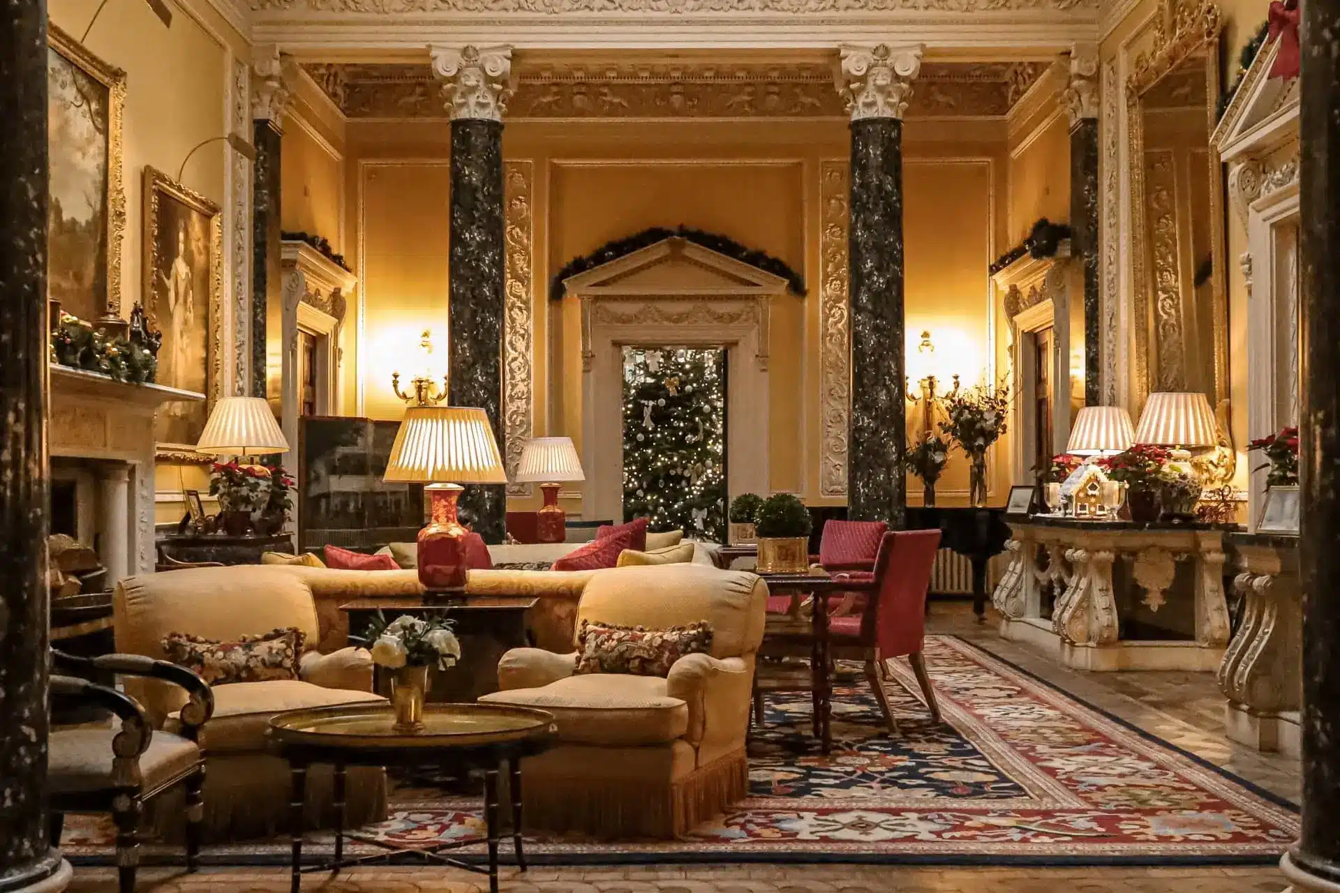 Ballyfin’s ornate drawing room, with a cream sofa, armchairs, lamps and a long patterned rug.