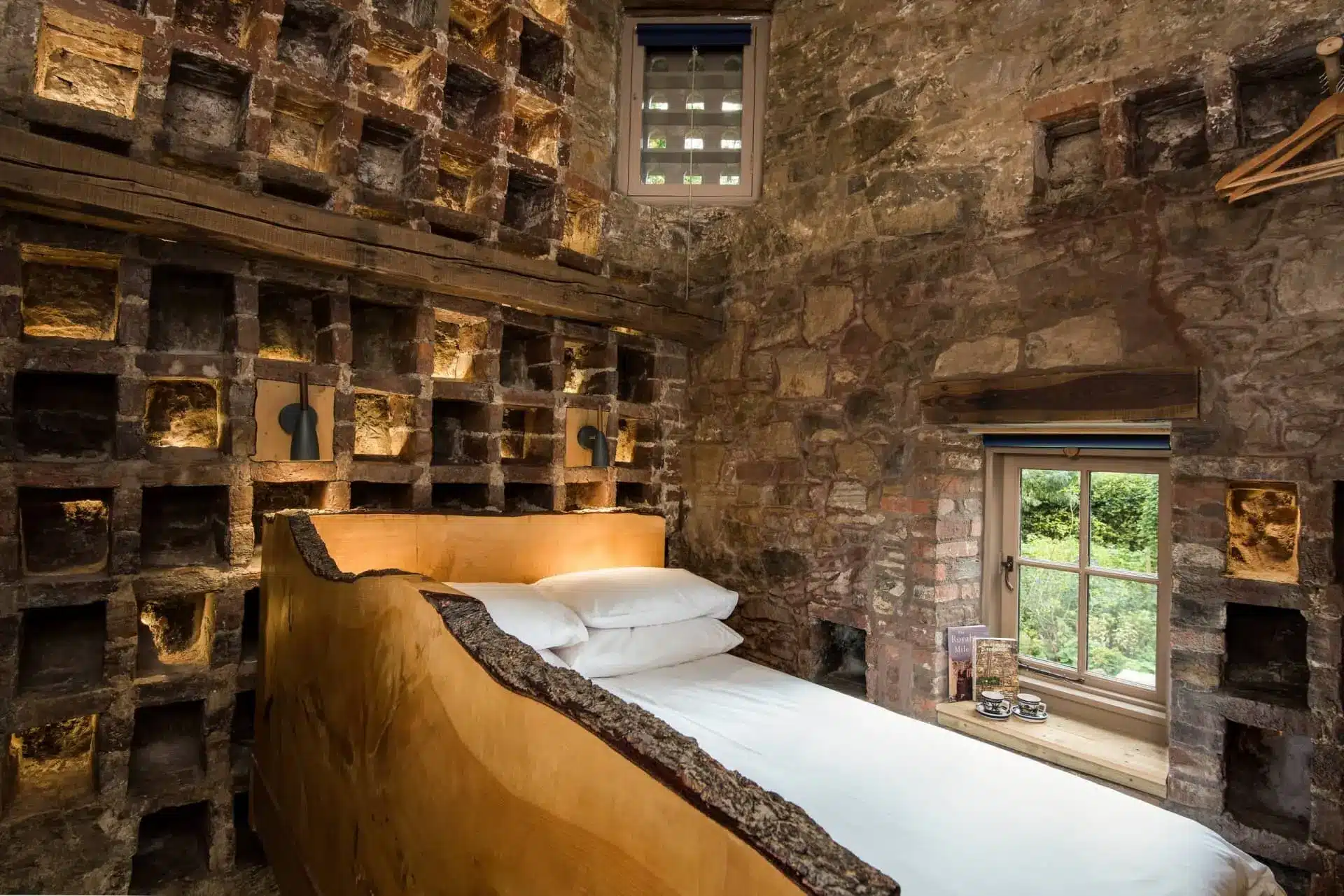 A bed sits among rows of stone nesting boxes in Dovecot Cottage’s tower bedroom.