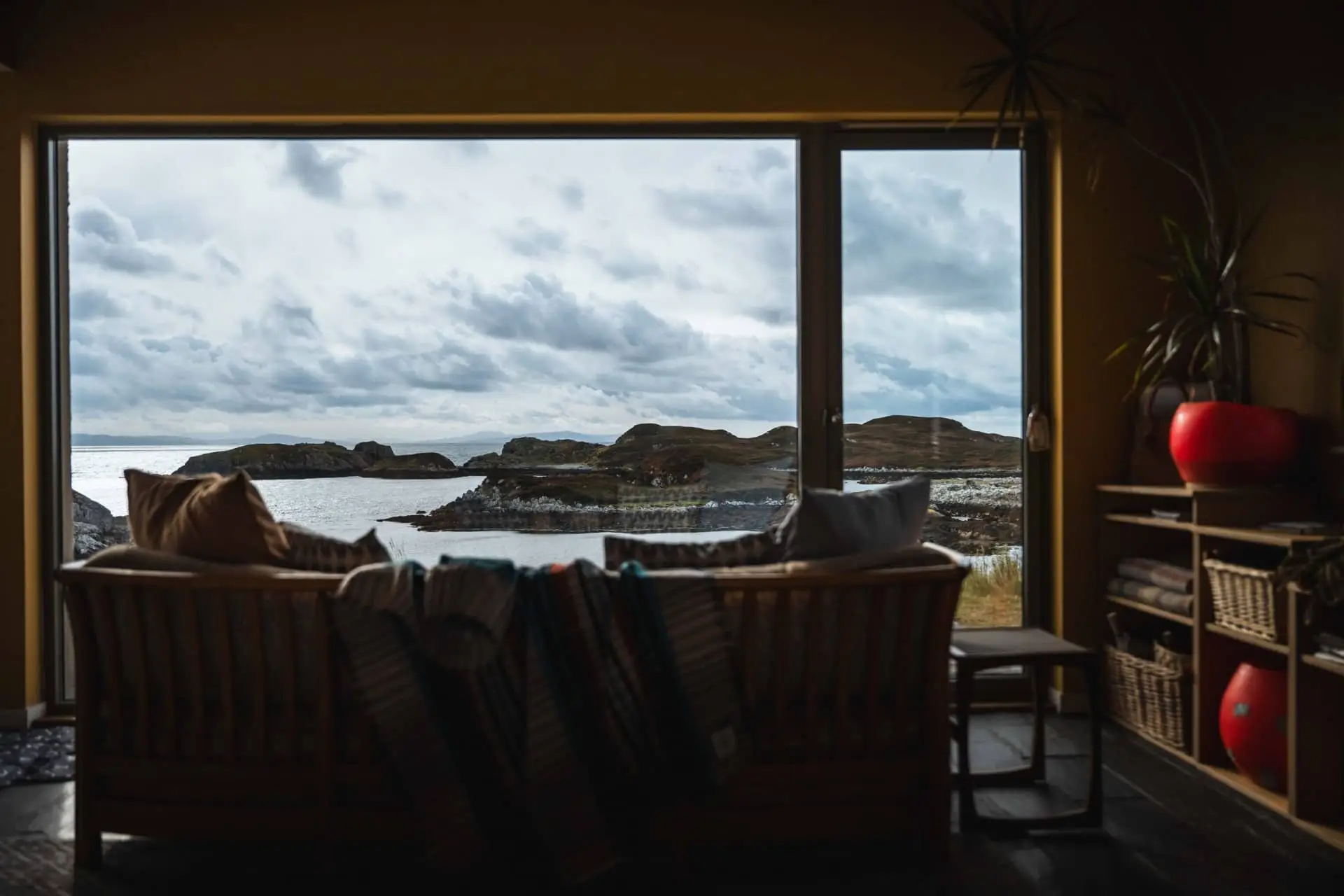 Dark living room with a sofa facing floor-to-ceiling windows overlooking the sea at Mol Bàn.