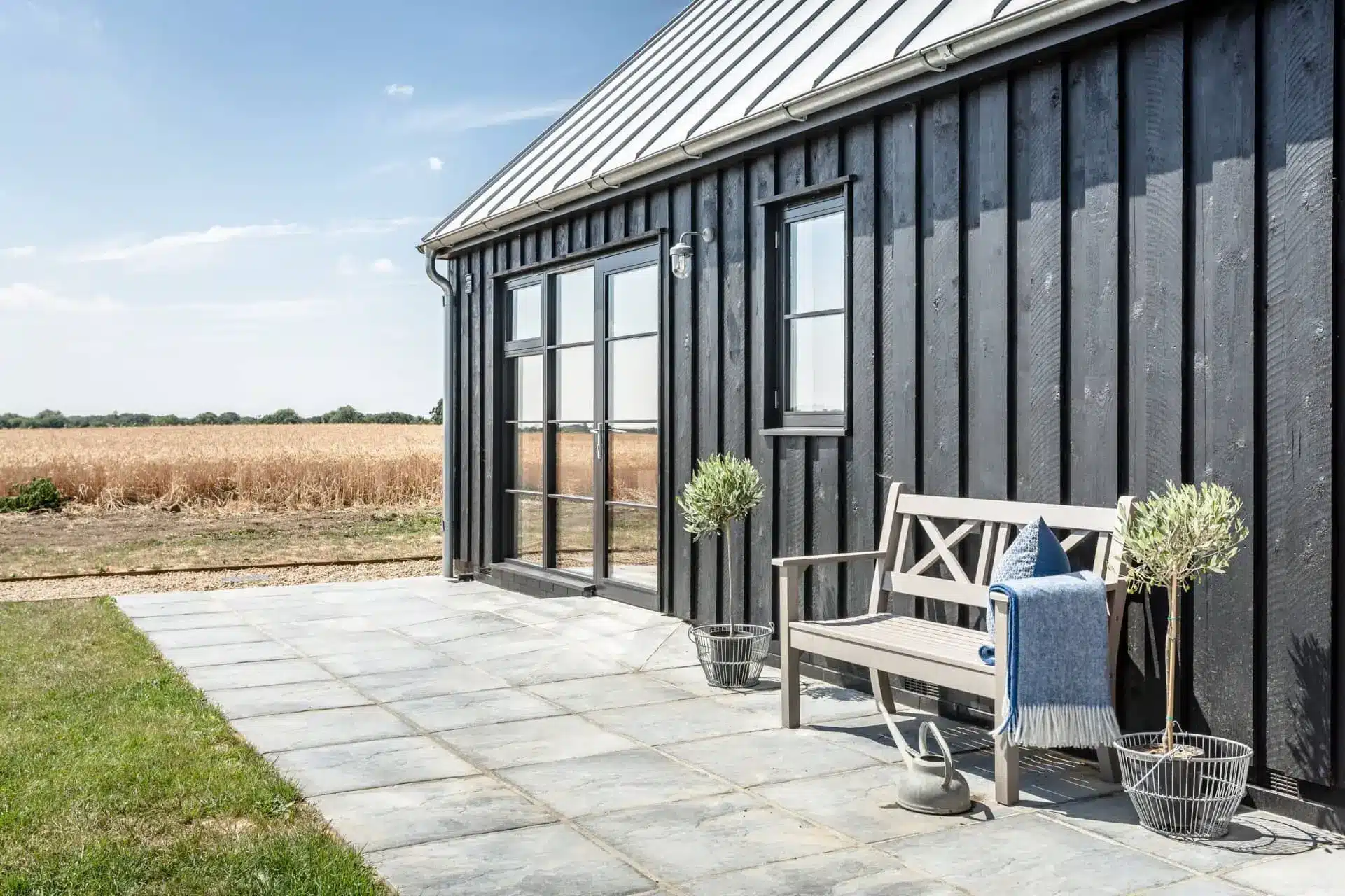Patio outside Millers, an architect-designed barn, with glass doors, outdoor table and chairs, and a lawn.