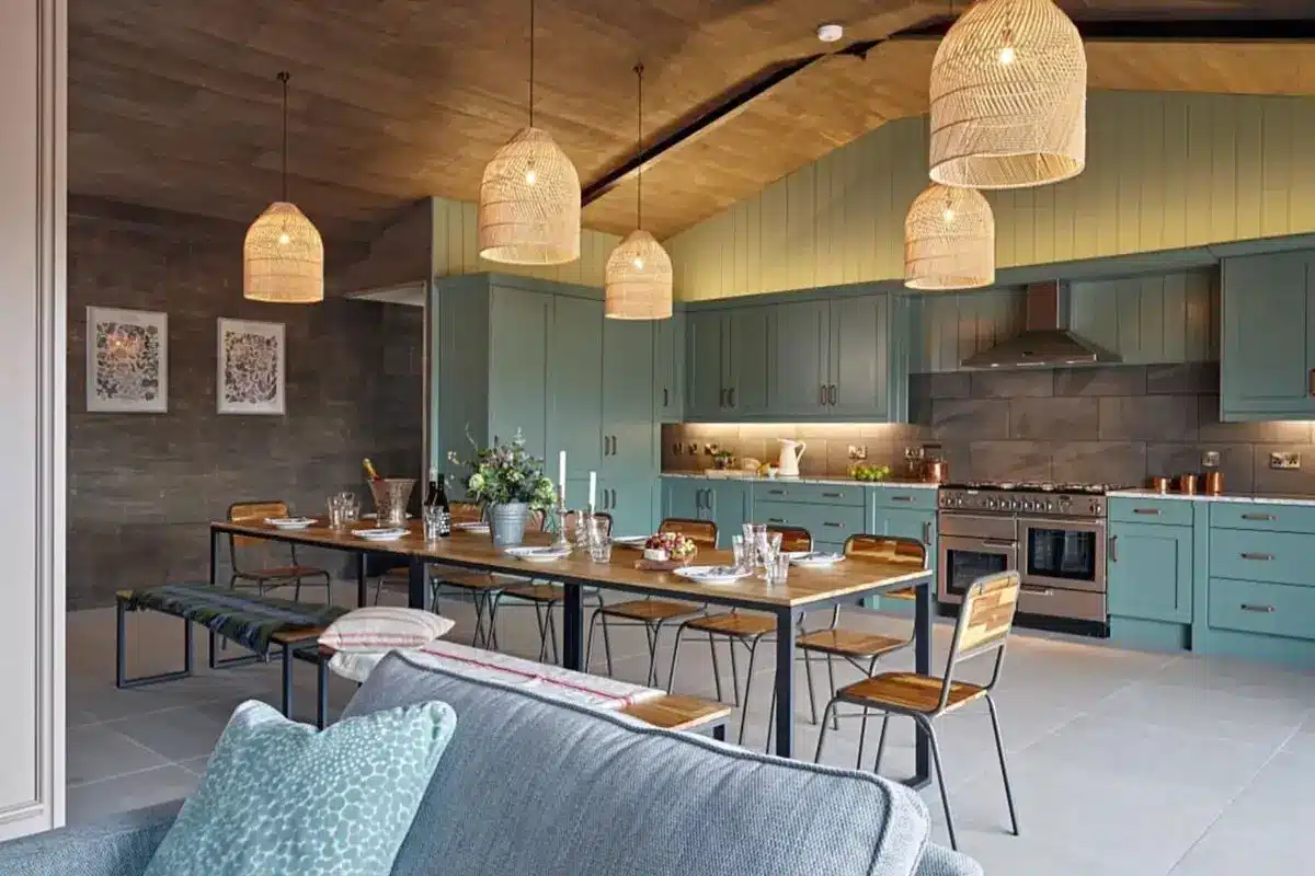 Coastal-inspired luxury kitchen with woven pendant lights, a long island, and a blue living room sofa