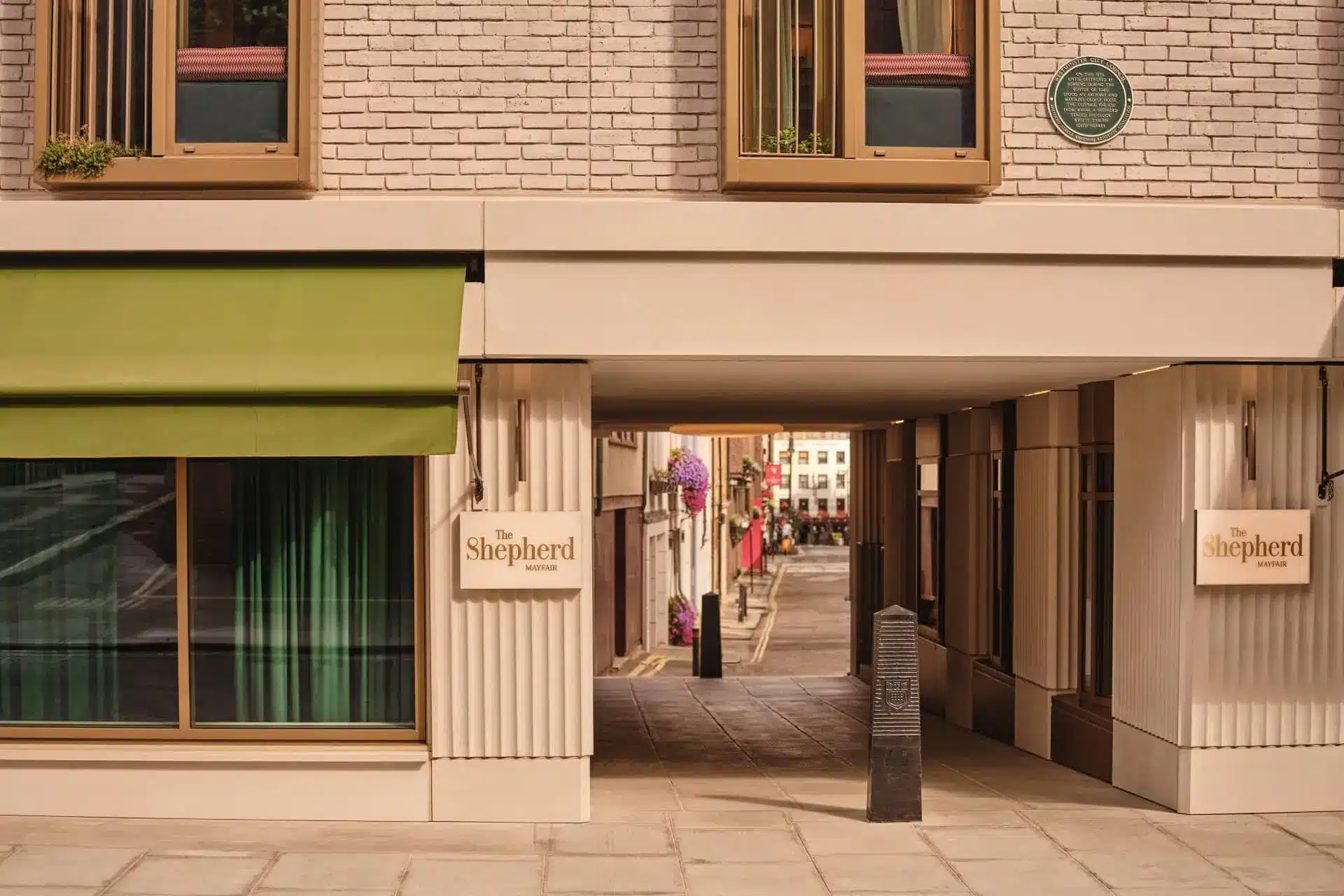 Illustrated entrance to The Shepherd Mayfair, with a tiled walkway leading past Shepherd signs toward the hotel interior.
