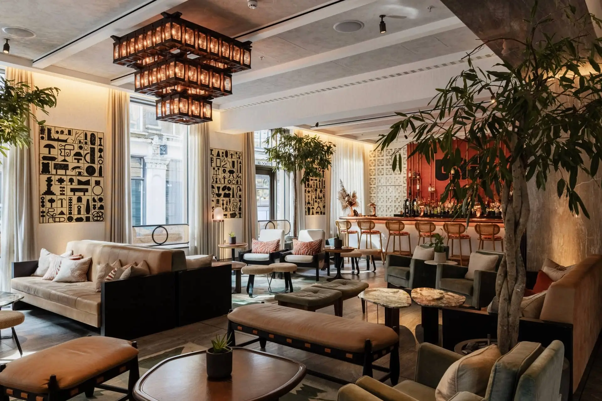 Elegant hotel lounge with plush sofas, sculptural chandeliers, and a leafy indoor tree