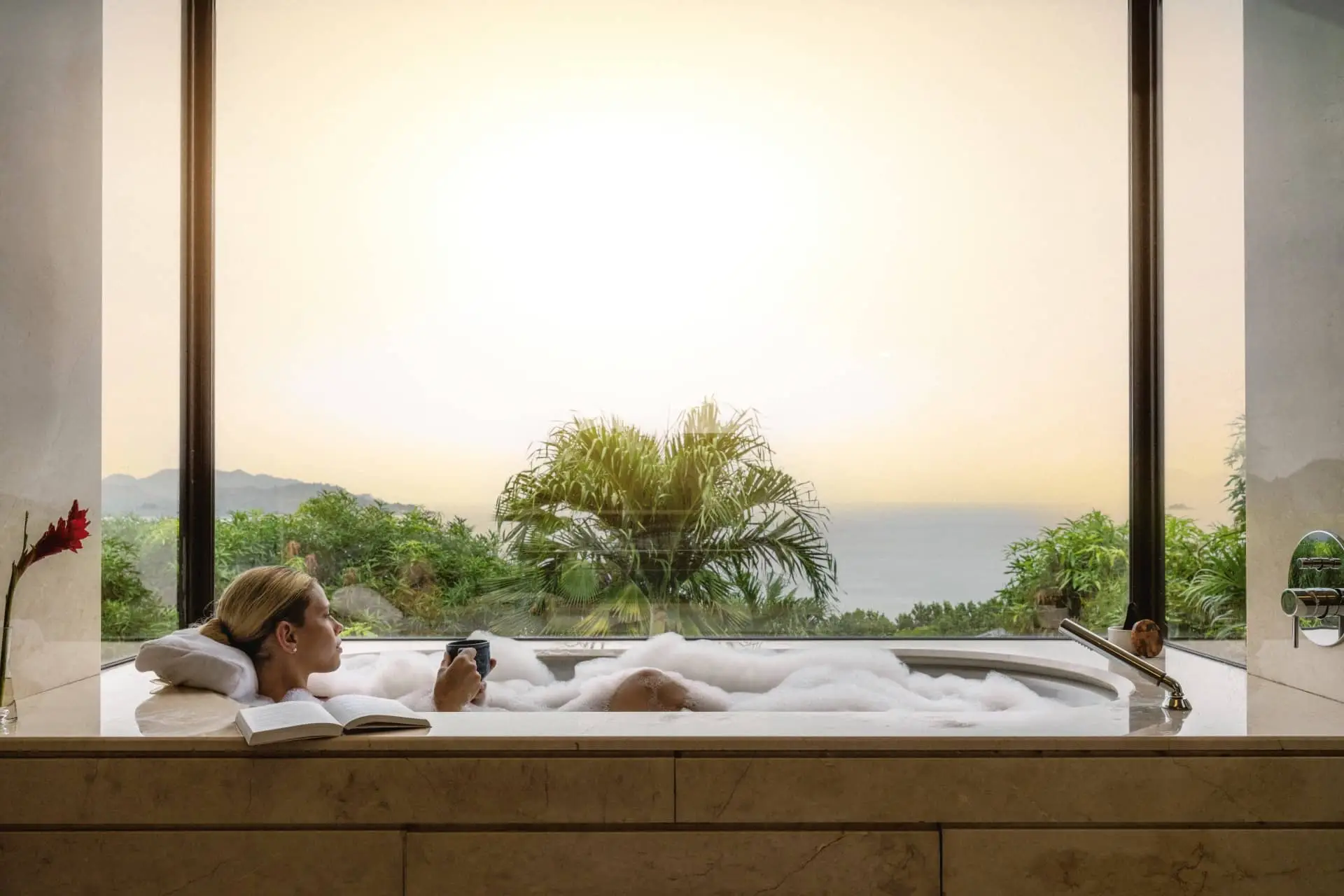A guest relaxes in a private infinity pool at Raffles Seychelles, overlooking palm trees and the ocean.