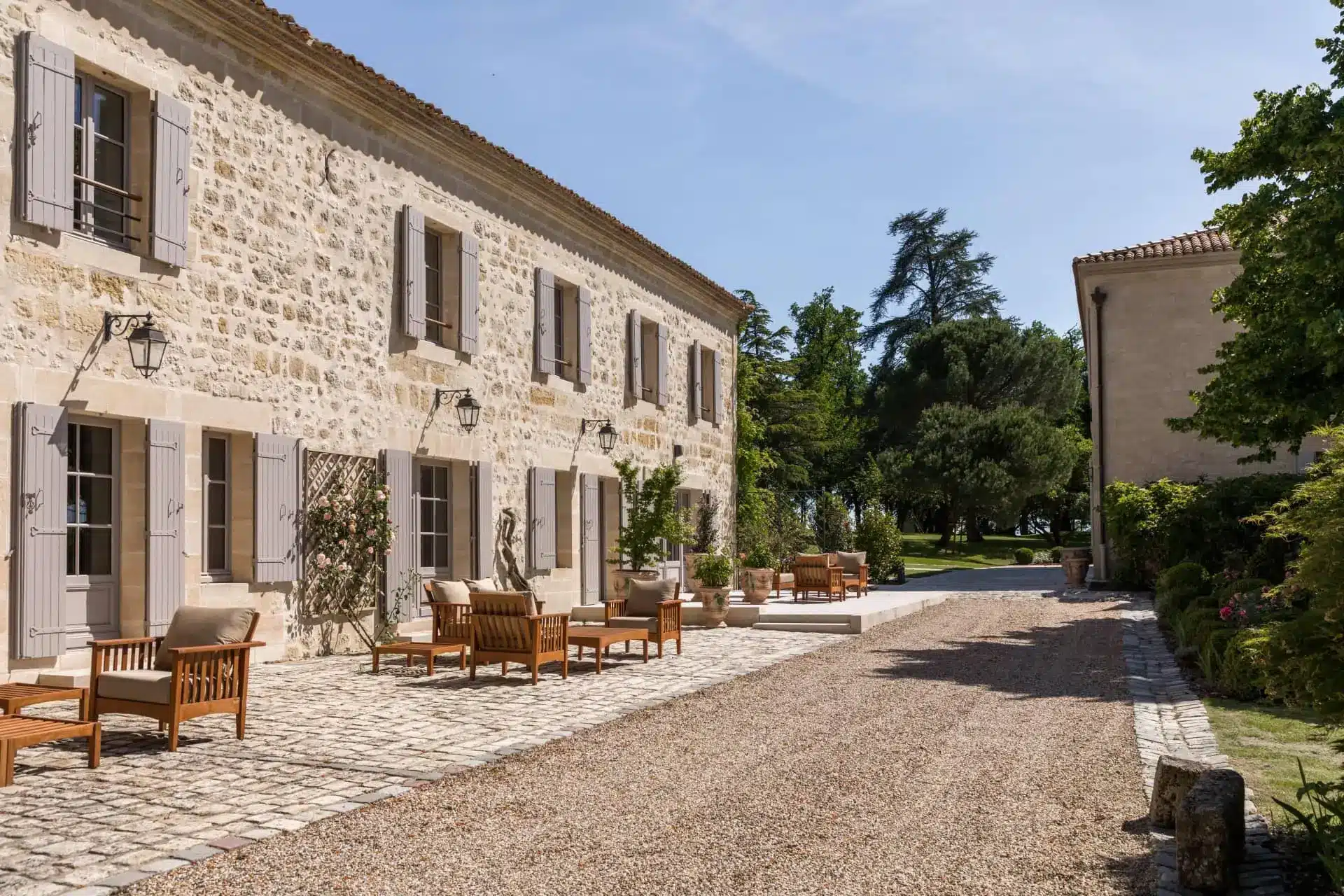 Stone terrace outside Château Troplong Mondot, with outdoor tables and chairs overlooking the estate grounds.