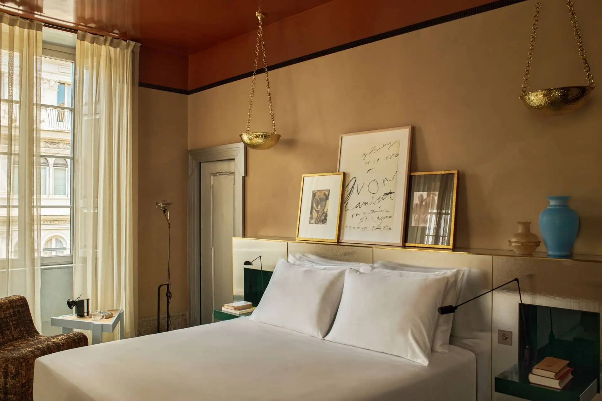 Quiet luxury bedroom with a king bed, framed artwork, and warm pendant lighting