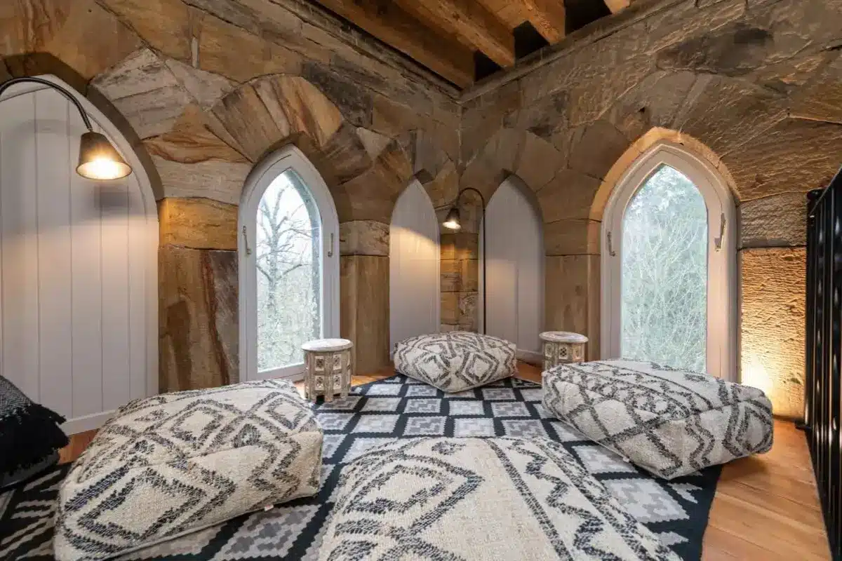 Luxury bedroom with arched windows, plush beds, and patterned rugs in a stone-walled retreat